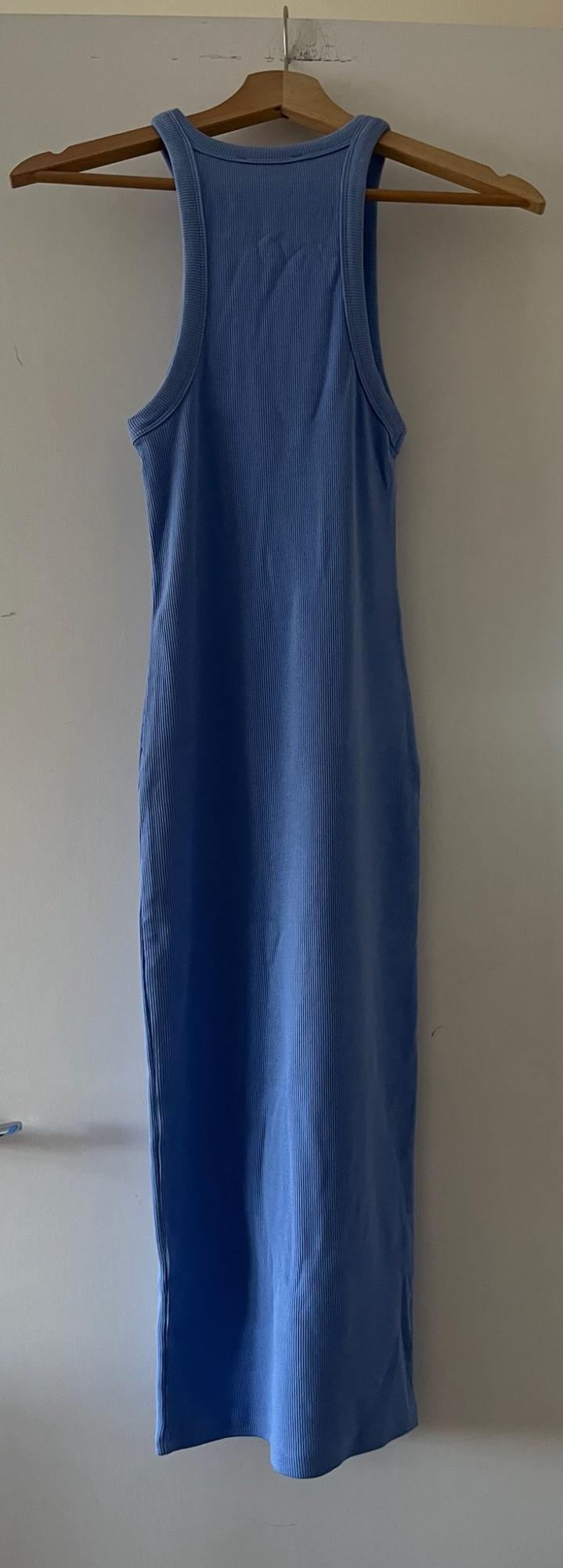 Light blue sleeveless ribbed maxi dress, hanging on a wooden hanger on a white door.