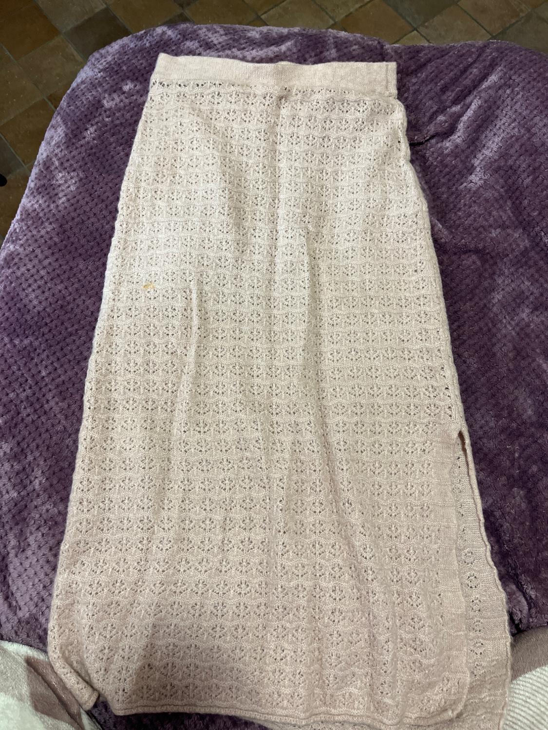 Long beige lace skirt on a textured purple blanket. Brown tiled background.