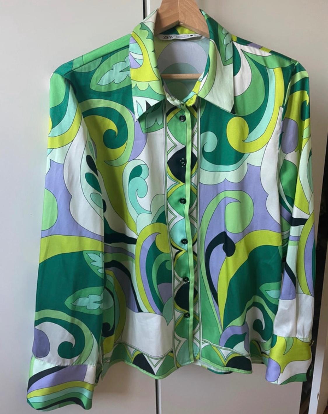 Long-sleeved shirt with a pattern of green, purple, white and black waves on a hanger. Label with the text ZARA visible.