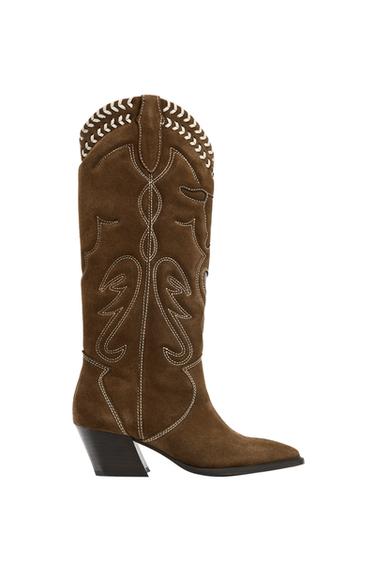 Side view of a brown boot with white embroidery, high shaft, medium-wide heel and pointed toe. Laced detail at the top.