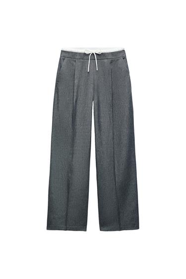 Front view of grey trousers with white drawstring and side pockets.
