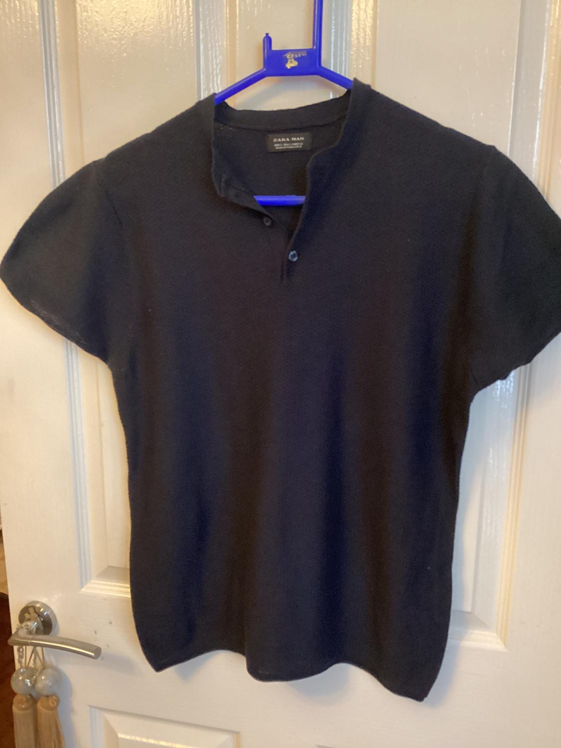 Front view of a black short-sleeved t-shirt with a button at the collar.