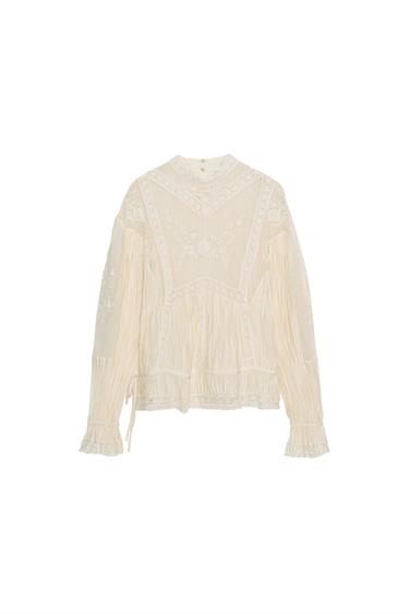 Front view of a raw blouse with a Perkins collar, long sleeves, and floral embroidery. Back button closure.