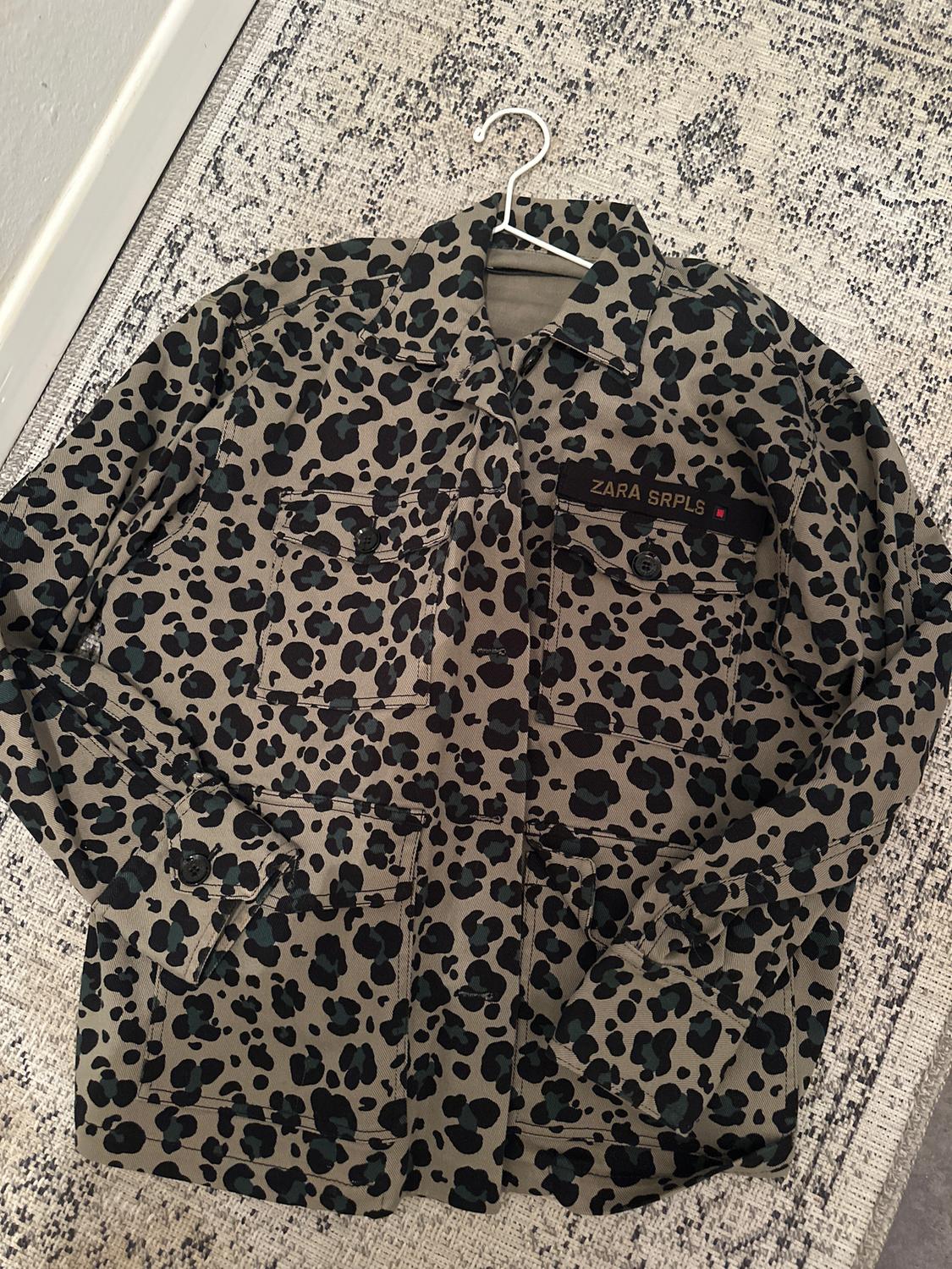 Jacket with a black spot print on a beige background, hanging on a hanger. Visible text: "ZARA SRPLS".