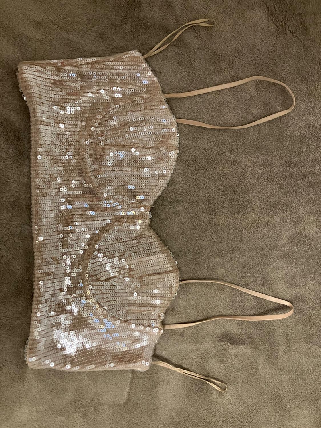 Beige sequinned crop top with thin straps, laid out flat on a soft light brown blanket.