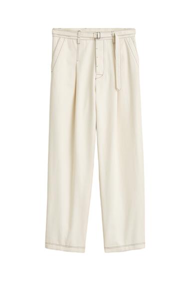 Front view of ecru trousers with a belt, side pockets, and front pleats.