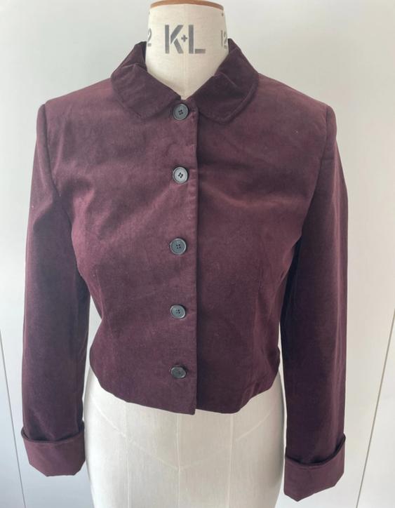 Mannequin with a short, burgundy velvet jacket, round neck and black buttons. White background. Visible text: "K+L".