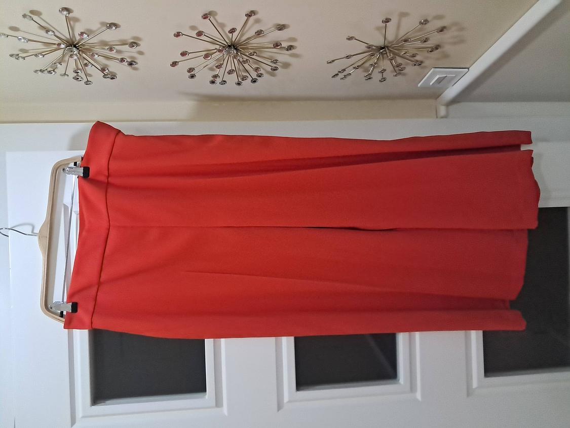 Long red skirt hanging on a hanger over a white door, with star-shaped metallic ceiling decoration.