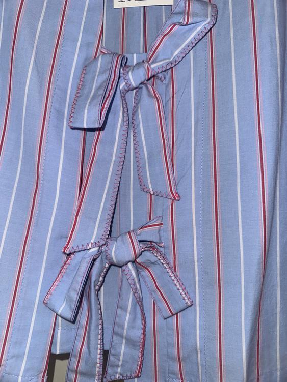Blue, white, and red striped shirt with two bows on the front.