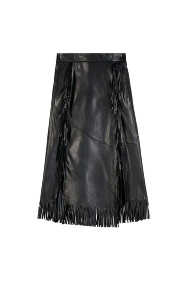 Black midi skirt with asymmetrical seams and long decorative fringe on the front and hem, against a white background.