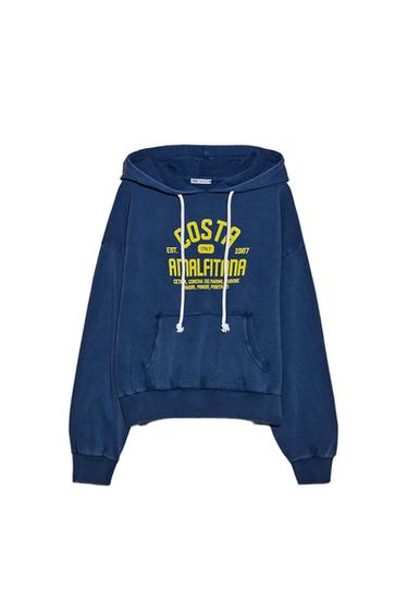 Blue hoodie with a hood and white drawstrings. Yellow text: "Amalfi Coast, Italy, Est. 1987, Cetara, Conca dei Marini, Furore, Maiori, Minori, Positano".