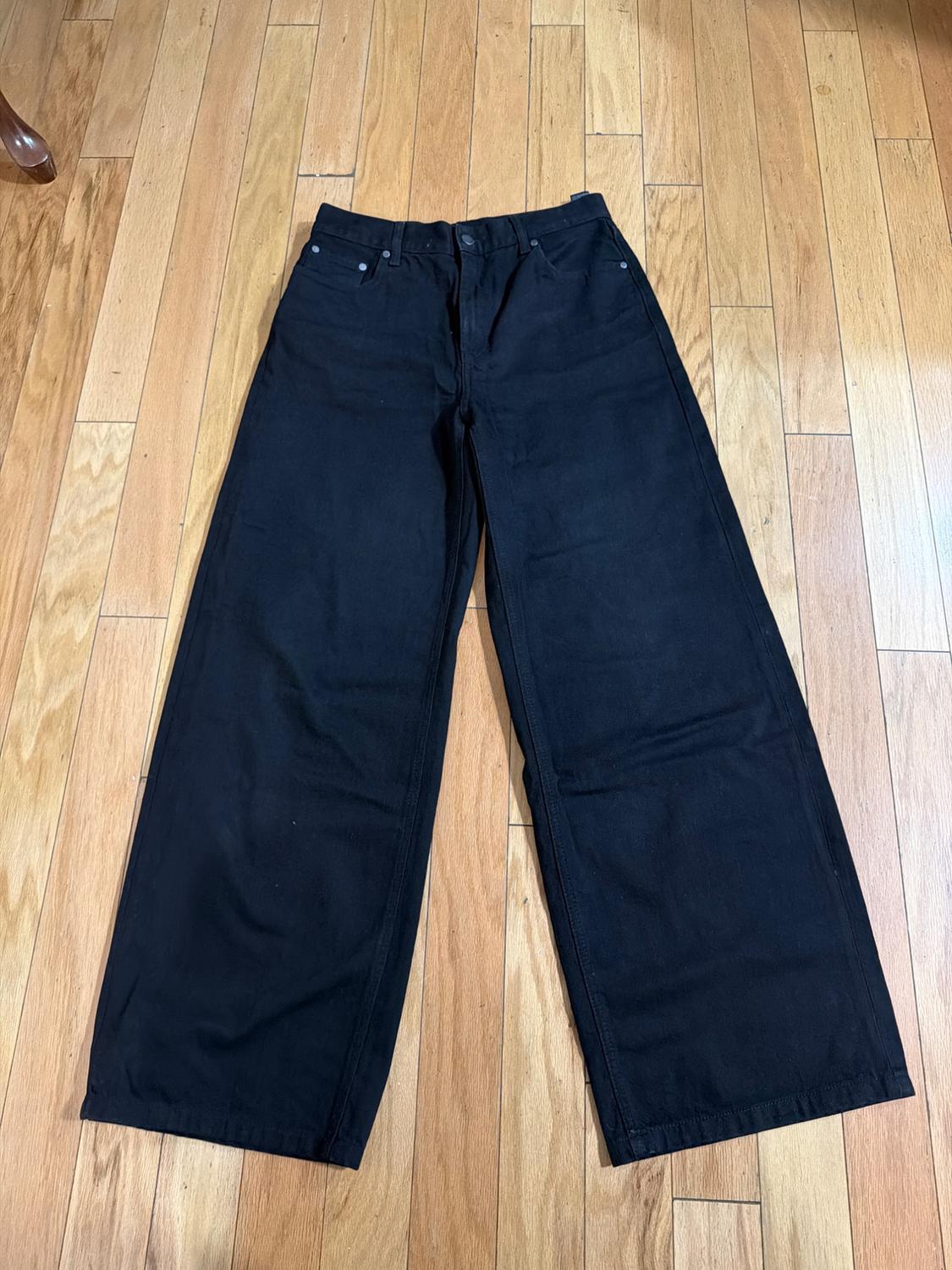 Black wide-leg pants on a light wooden floor.