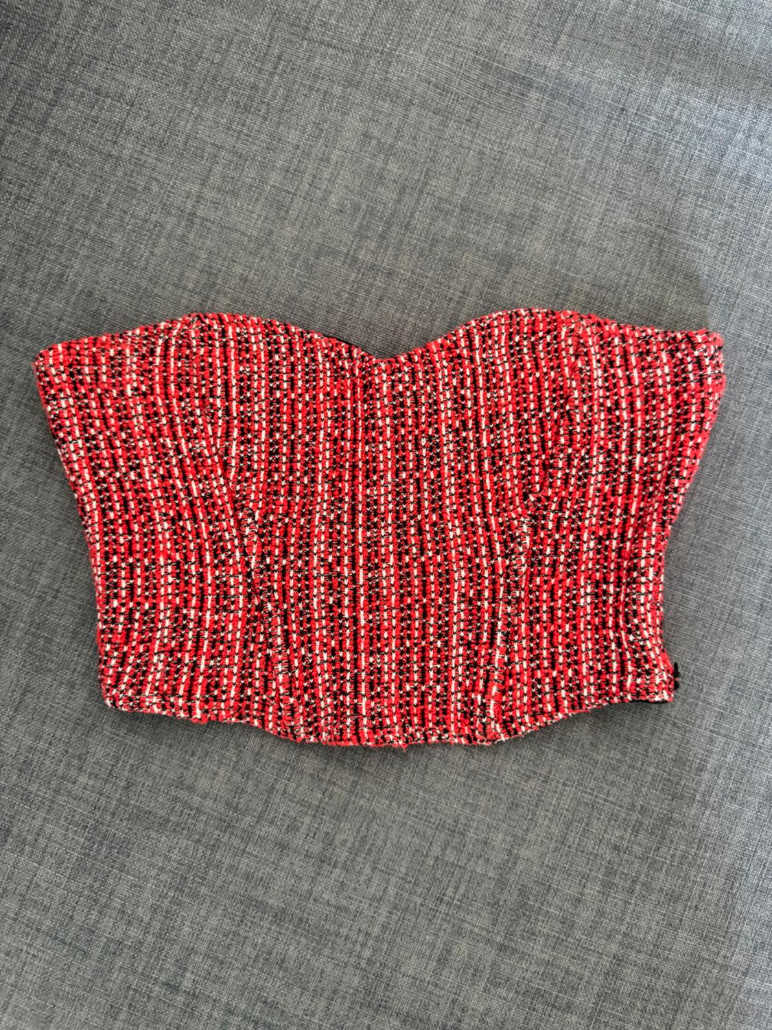 Strapless sweetheart neck crop top in textured red, black, and white fabric, on a grey fabric background.