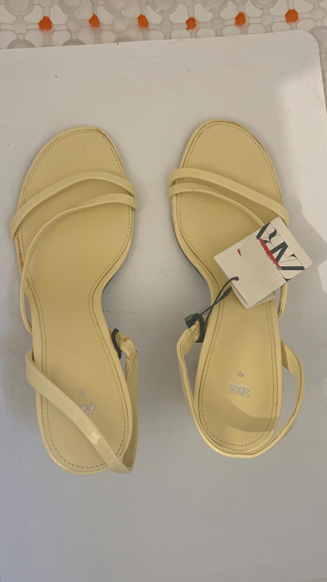 Pair of yellow heeled sandals with thin straps on a white surface. They have a label with the text ZARA and an insole with ZARA 41.