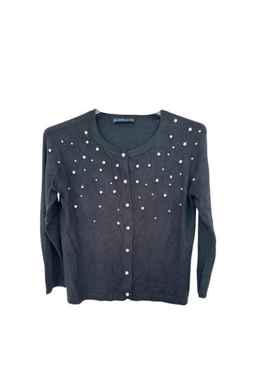 Front view of a black cardigan with decorative pearls on the chest and a central button fastening.