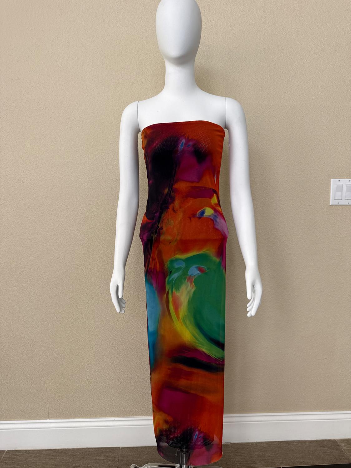 White mannequin wearing a long, strapless dress with a vibrant multi-color abstract print in front of a beige wall.