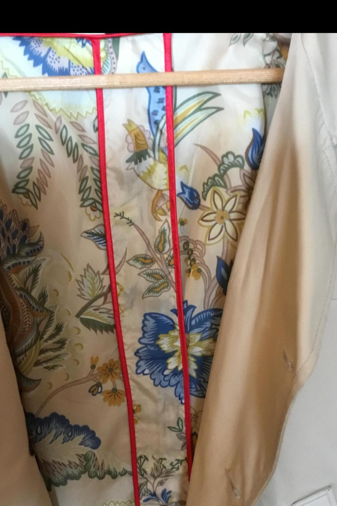 Floral lining detail with red trim on beige garment.