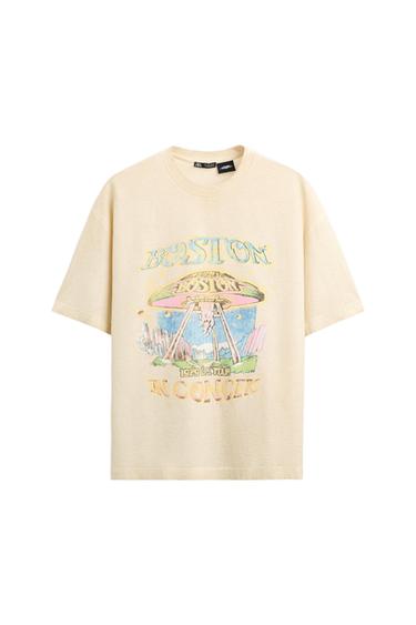 Beige T-shirt with a graphic design of a spaceship and the text "BOSTON 1979 1ST TOUR IN CONCERT" in pastel colours.