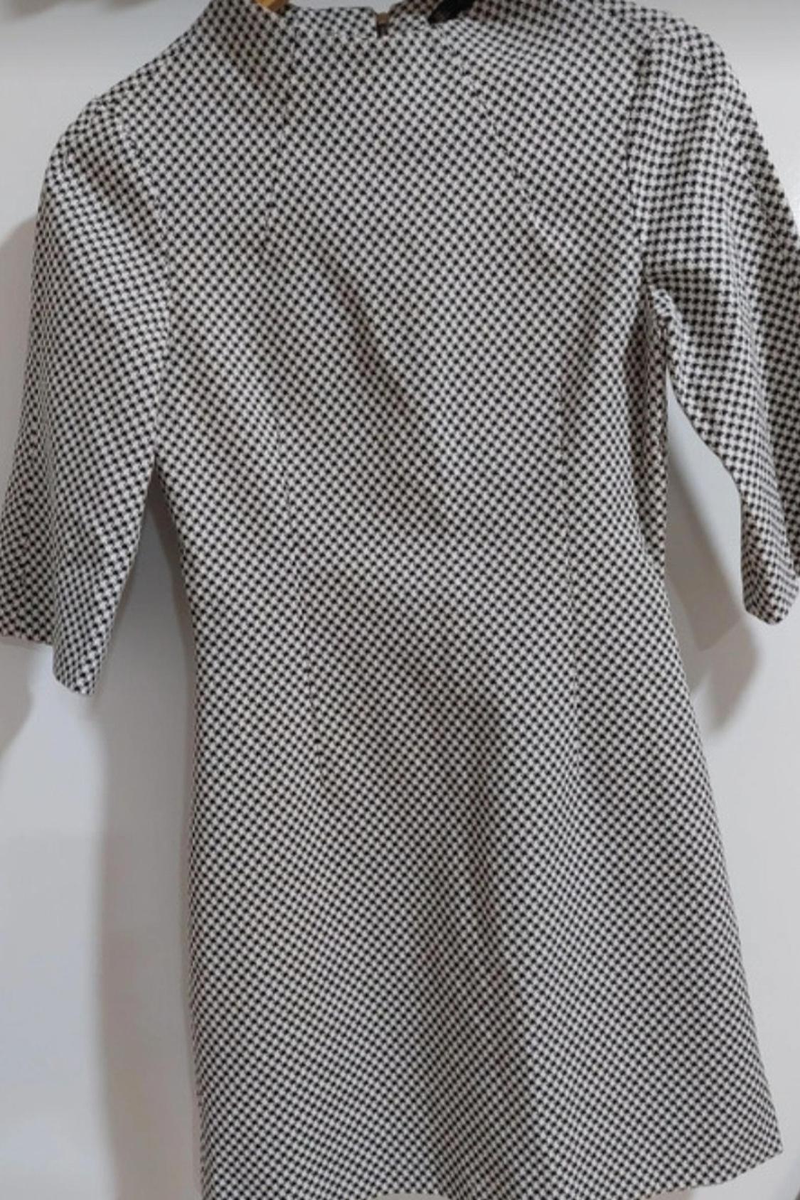 Front view of a black and white small check print dress with three-quarter sleeves.