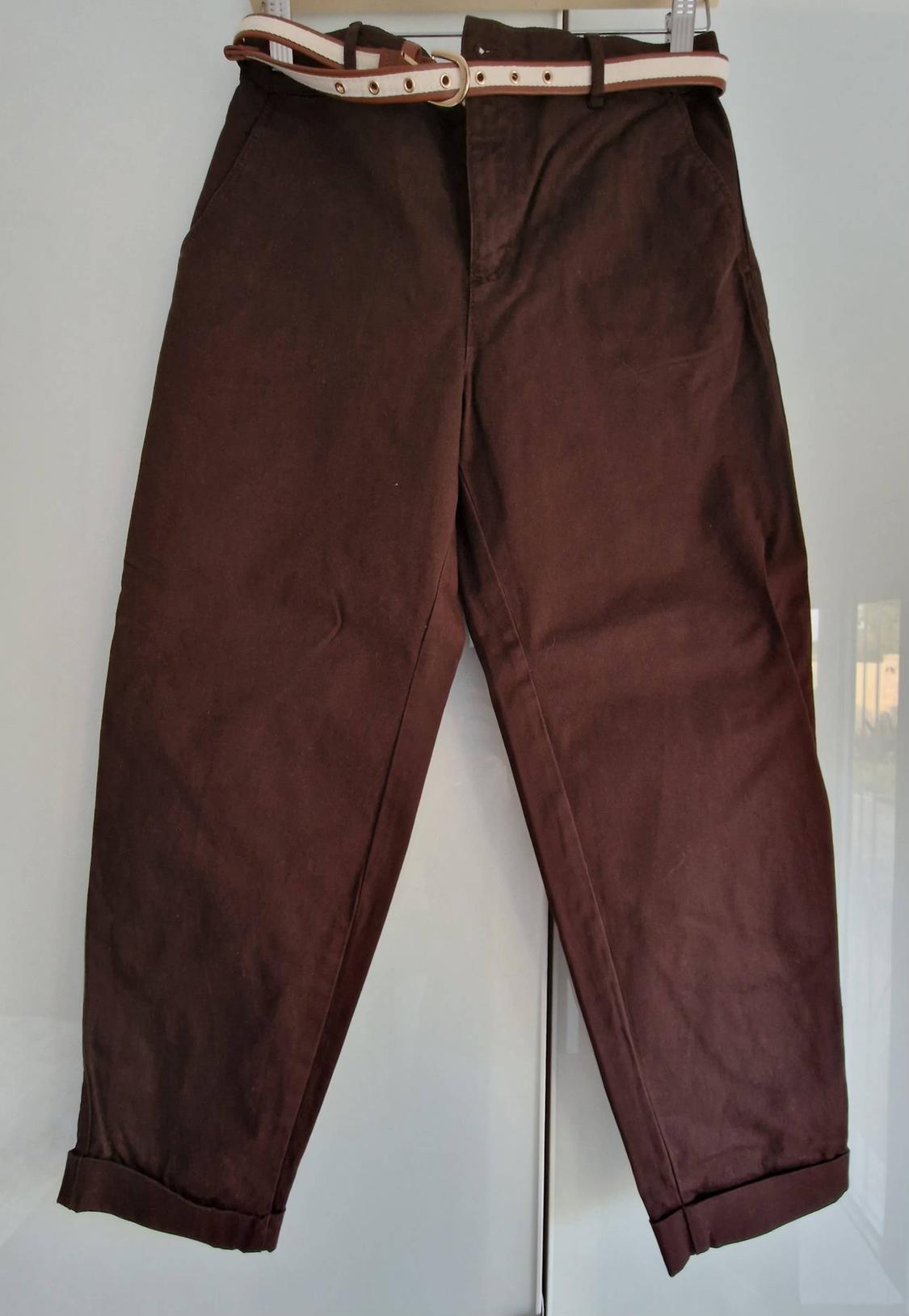 Brown trousers with a hemmed bottom and a beige belt with brown details, displayed against a white background.