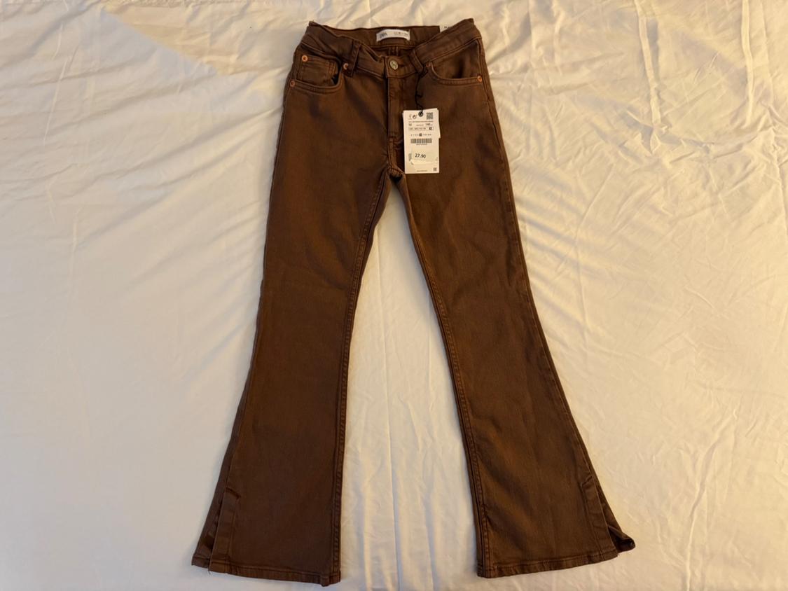 Front view of brown flared pants with front pockets and visible tag.