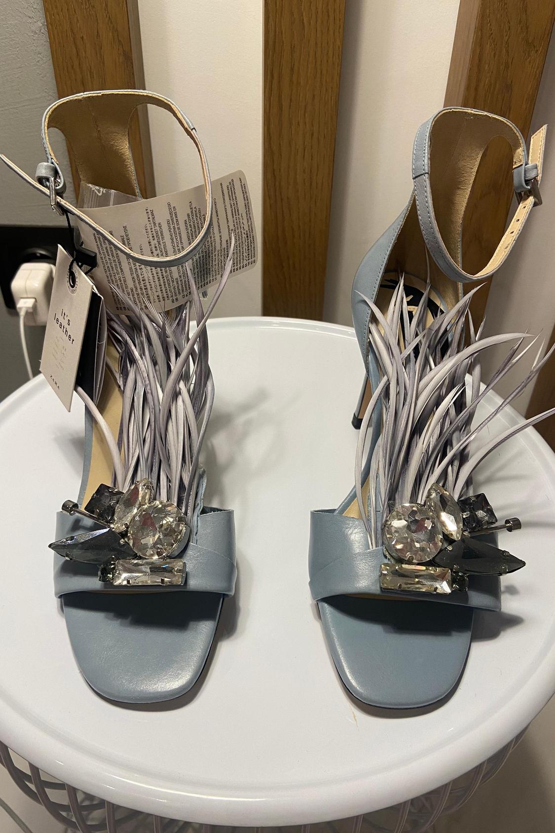 Blue high-heeled sandals with decorative feathers and crystal embellishments on the vamp.
