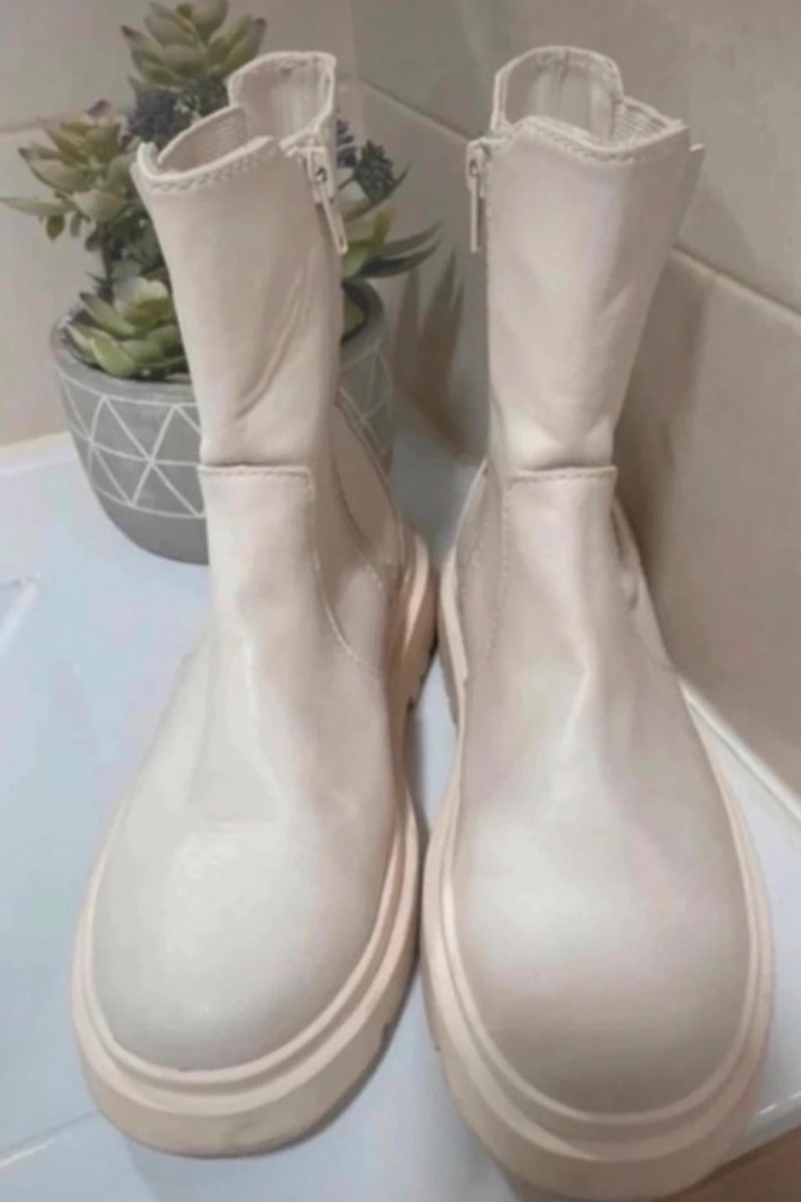Front view of white boots with side zip.