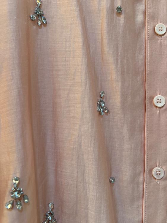 Light pink fabric with white buttons and shiny cluster-shaped rhinestone embellishments.