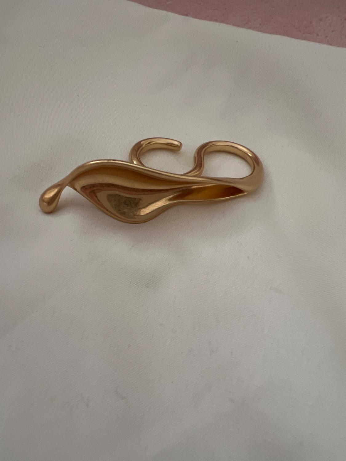 Detail of a wavy gold accessory on a white background.