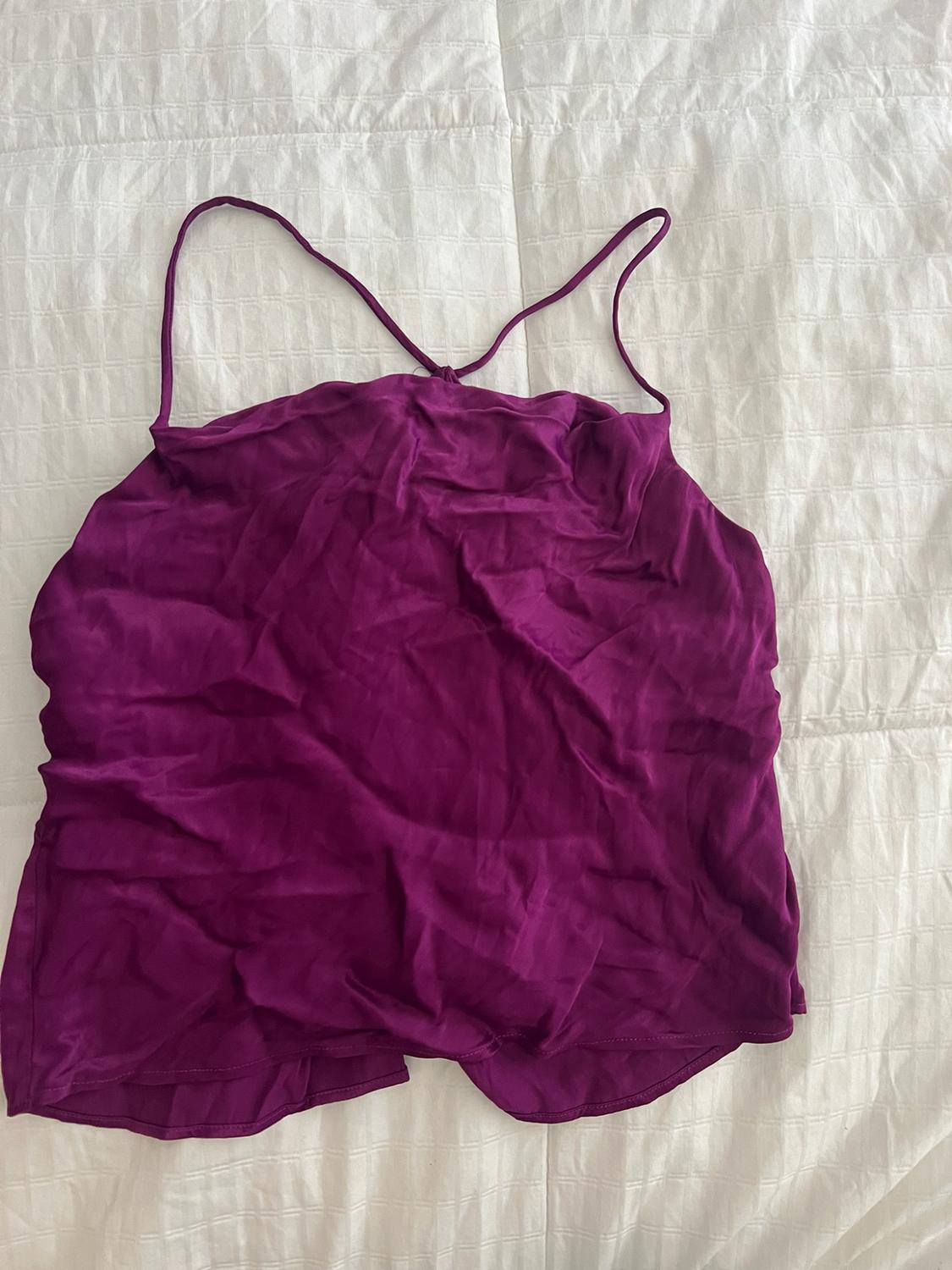 Purple spaghetti strap top in crinkle fabric, laid out on a textured white surface.