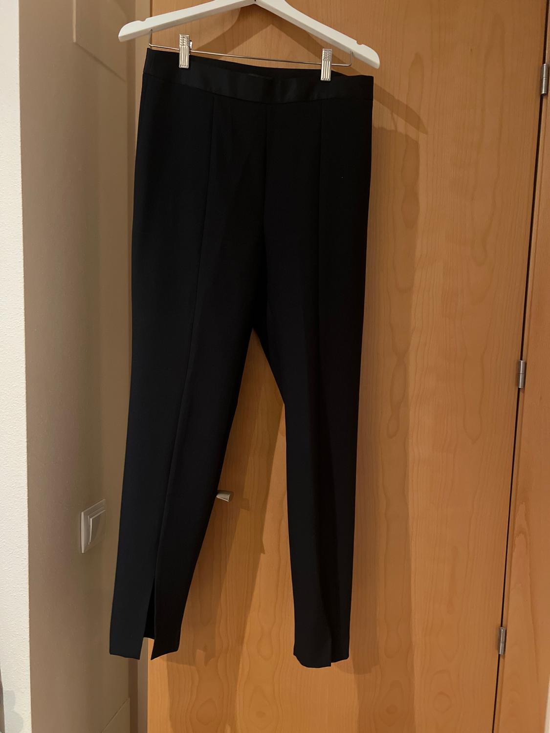 Front view of black pleated trousers with a straight cut.