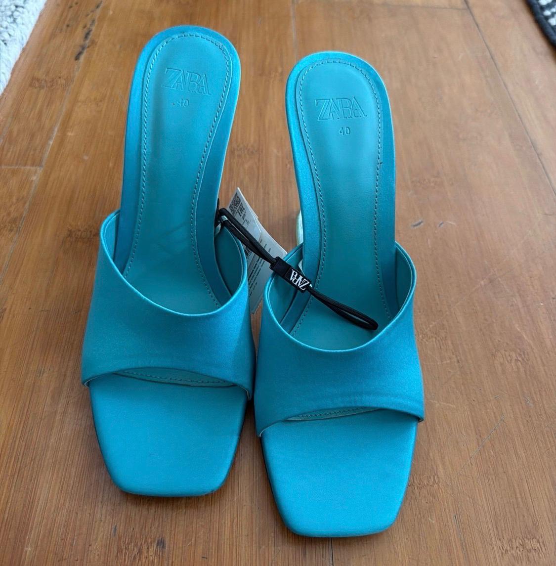 Turquoise-blue square-toe heeled sandals on a wooden floor. Visible text: ZARA 40 ZARA 40 ZARA.
