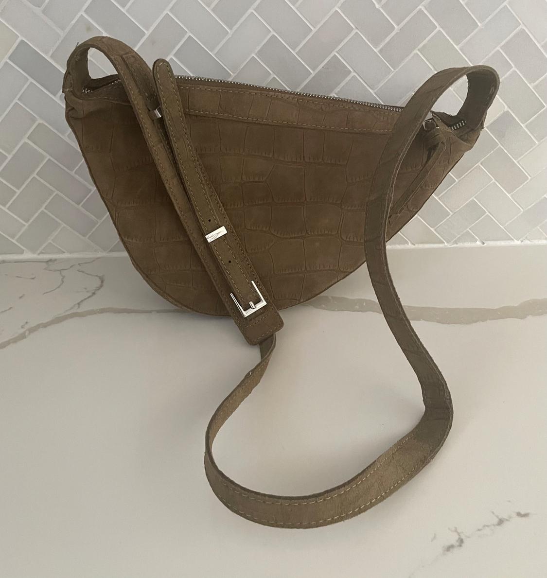 Front view of a brown handbag with crocodile texture and an adjustable strap.