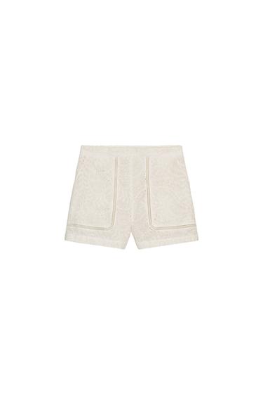 Front view of white Bermuda shorts with perforated embroidery and side pockets. Side closure with concealed zip.