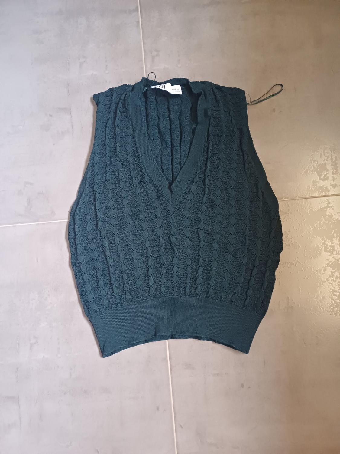 Front view of a dark green knitted waistcoat with a V-neck and diamond pattern texture.