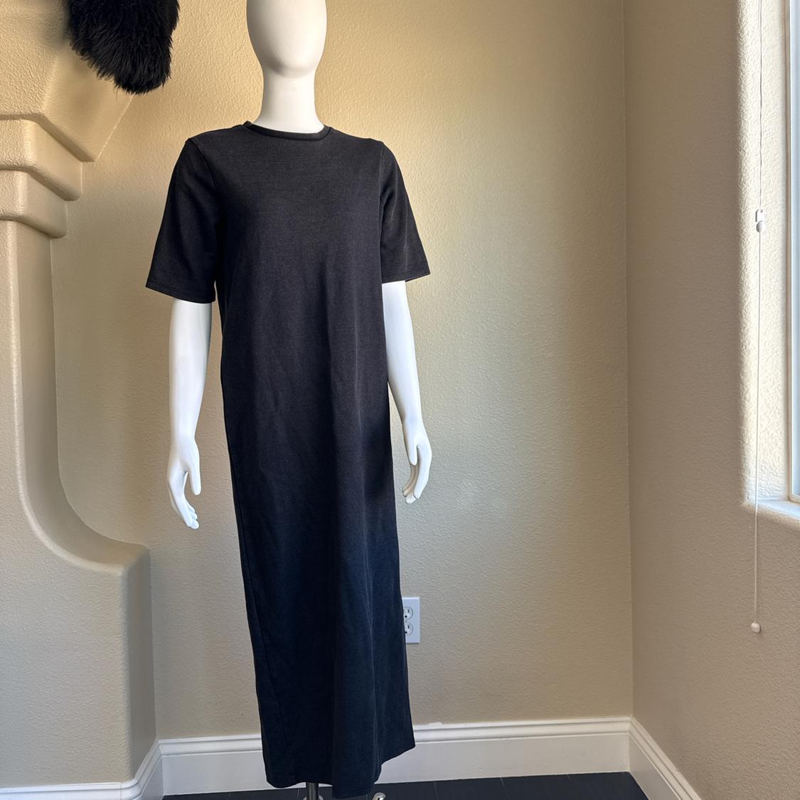 Mannequin in a black short-sleeved dress in a room lit by a window. Beige background with architectural details.