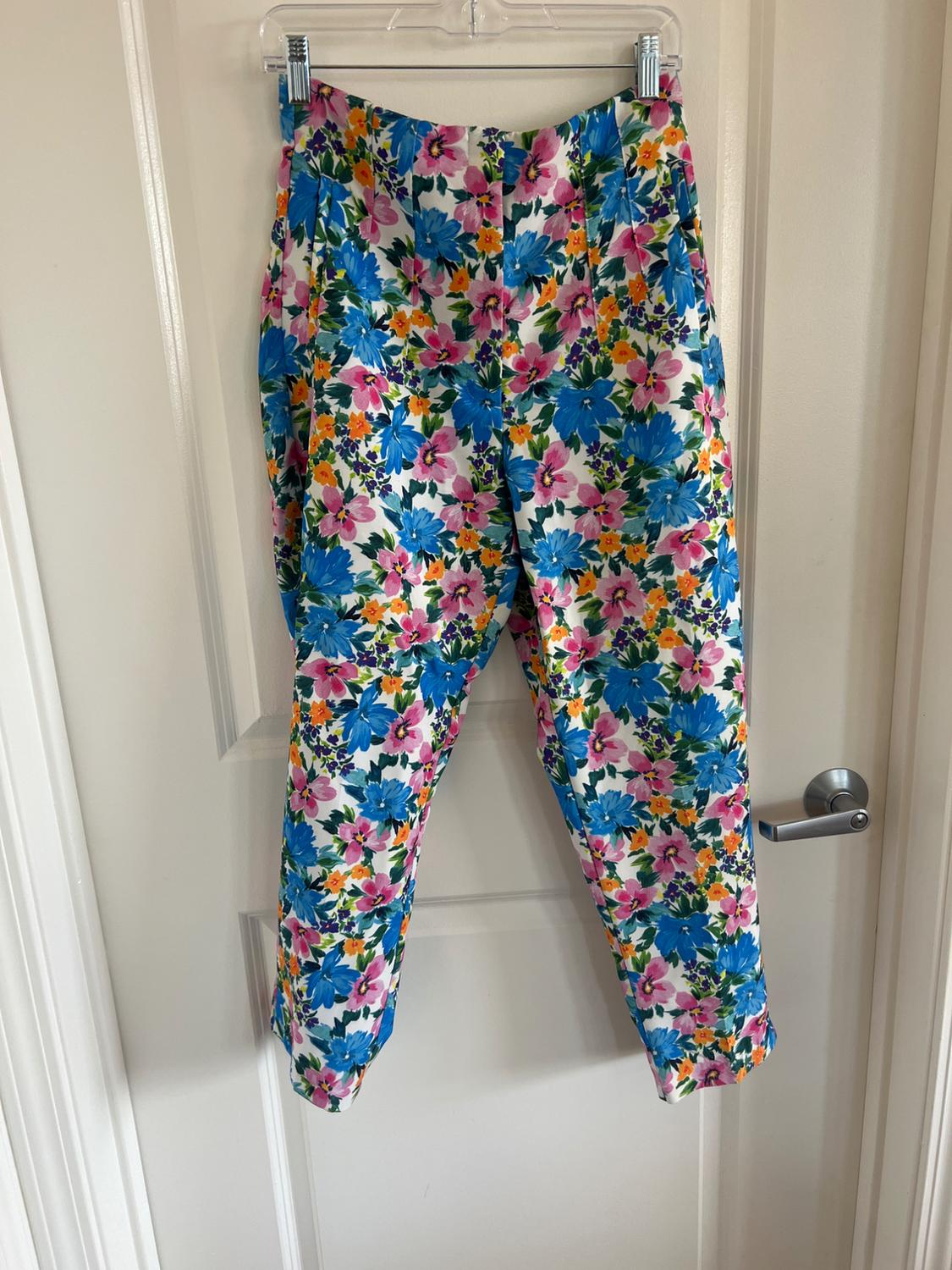 Front view of trousers with a multicoloured floral print, side pockets and a hem.