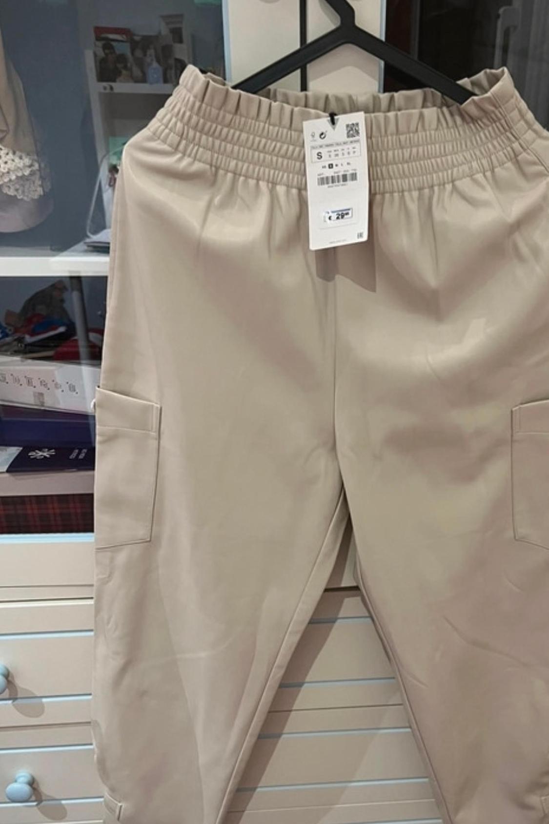 Front view of beige trousers with side pockets and an elasticated waist.