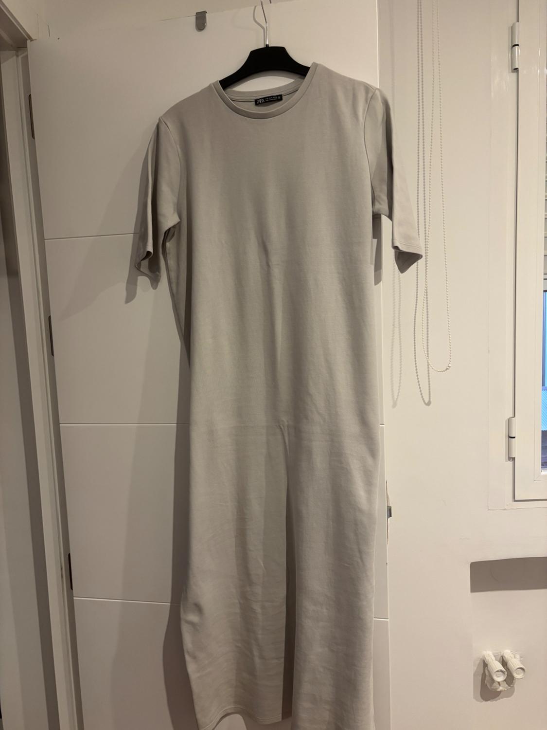 Light grey maxi dress hanging on a black coat hanger over a white door. Minimalist and simple setting.