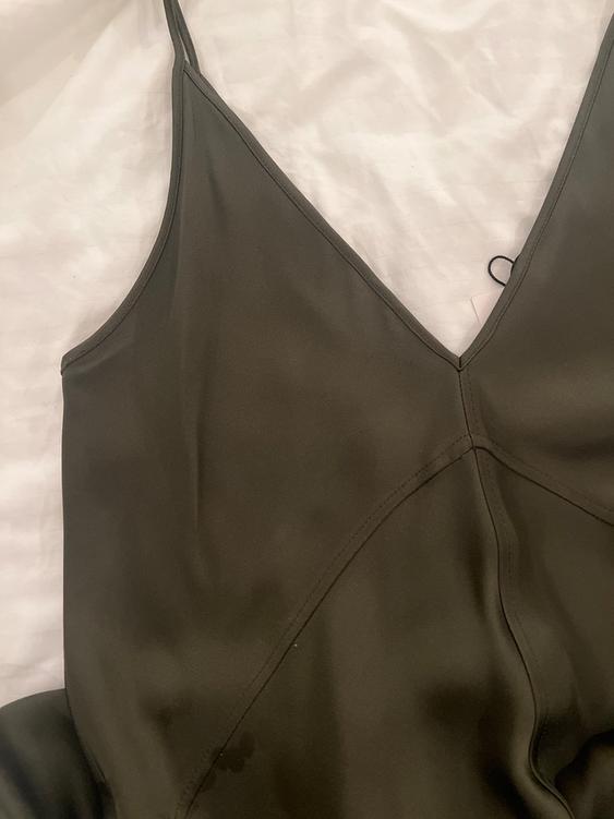Olive green strap dress on a white surface, with a V-neck and visible seams.