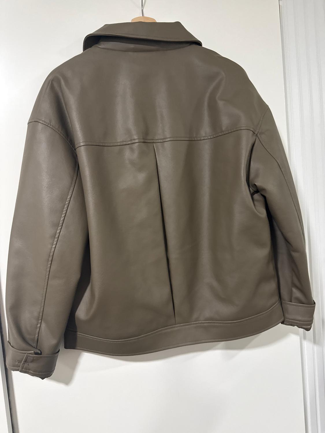 Brown faux leather jacket hanging on a hanger, seen from behind, with visible stitching and a simple design.