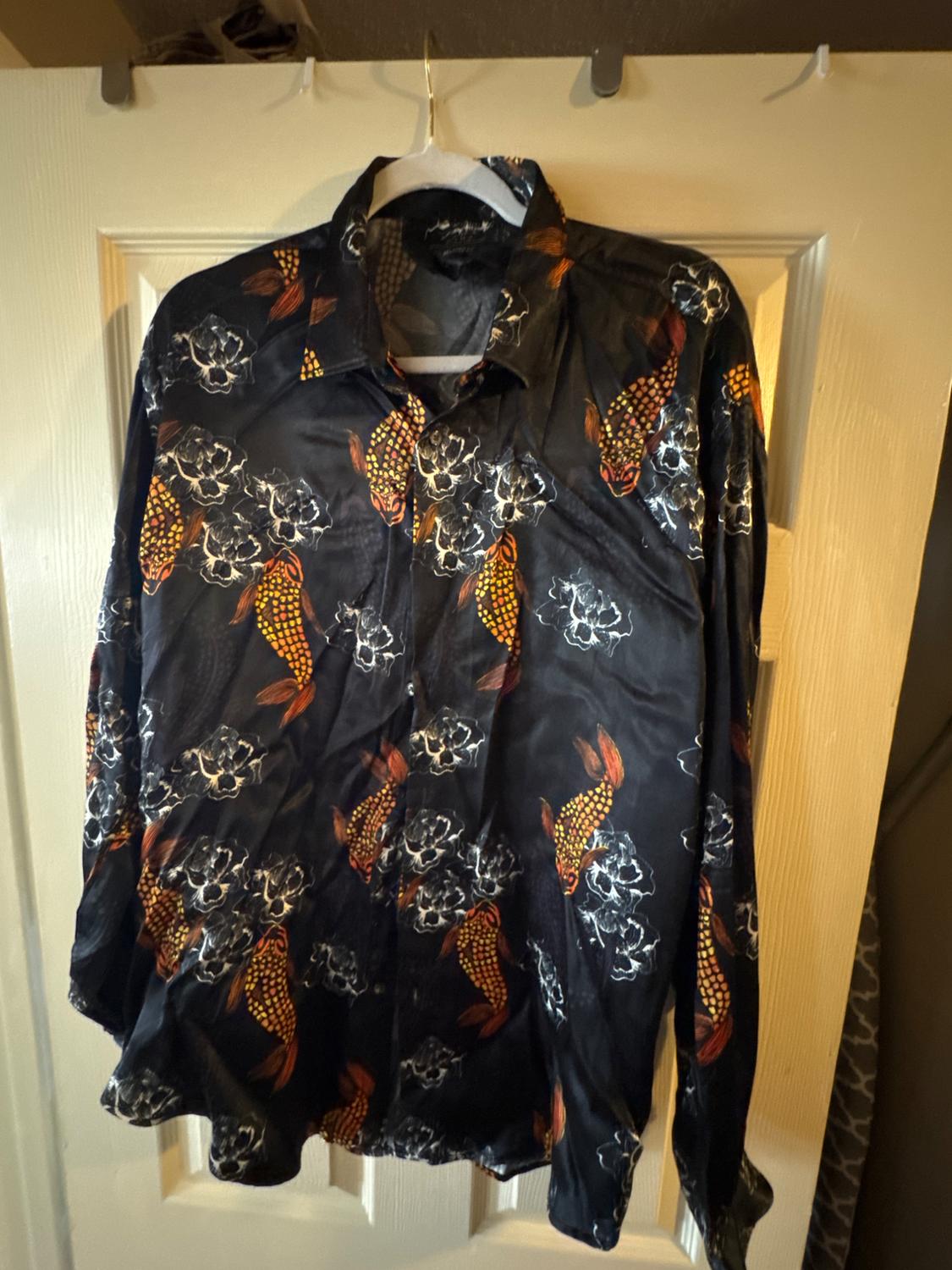 Long-sleeved shirt hanging on a door, with an orange koi fish and white floral pattern on a black background.