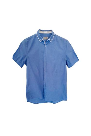 Blue short-sleeved shirt with a button-down collar and white trim detail. Visible label on the inside of the collar.