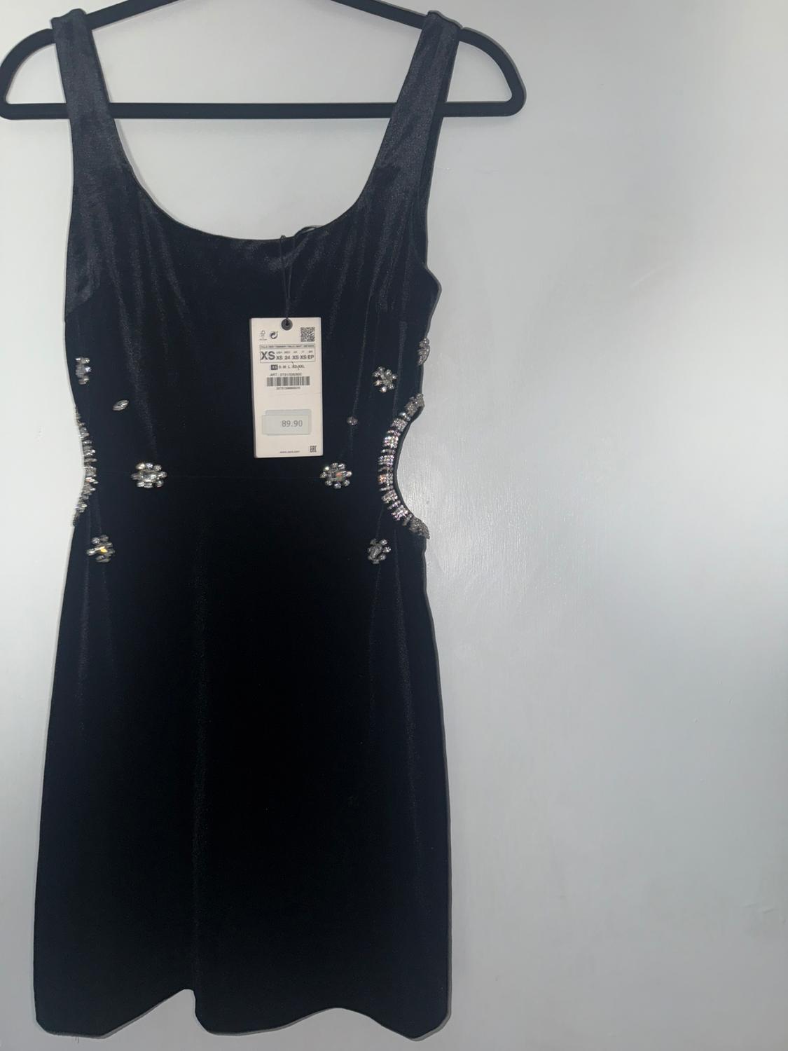 Black velvet dress with sparkly details on the sides, hanging on a hanger. Visible tag with price of 89.90.