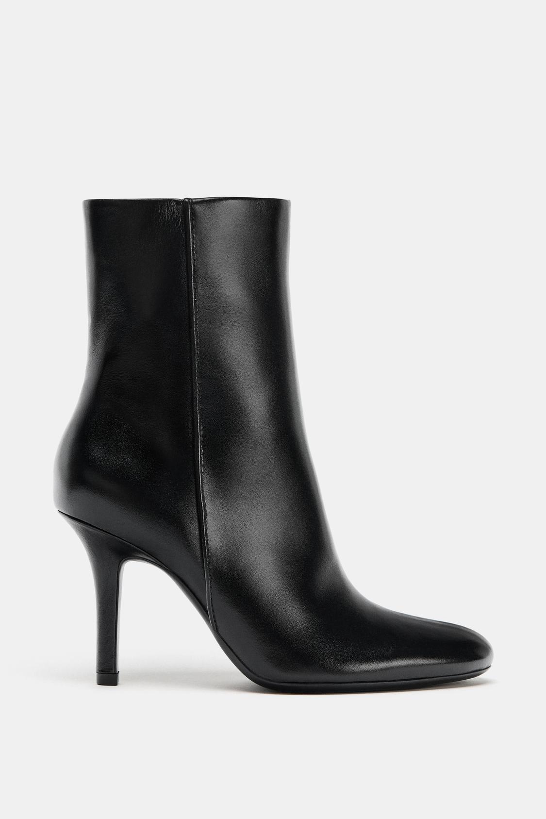 Side view of a black high-heeled boot with a rounded toe.