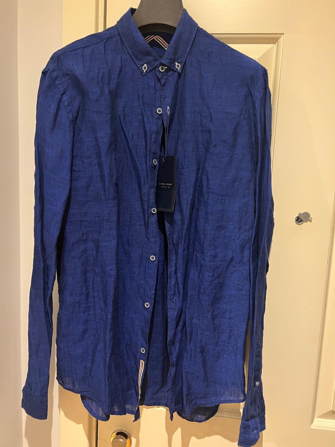 Front view of blue shirt with buttoned front and classic collar, visible label.