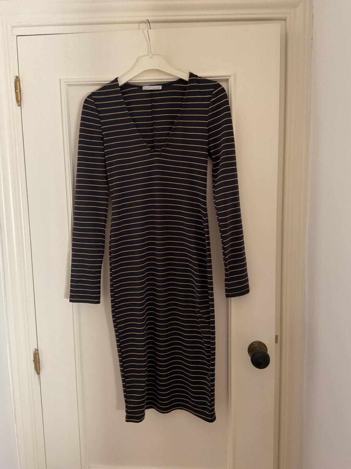 Front view of a black and white striped dress with a V-neck and long sleeves.