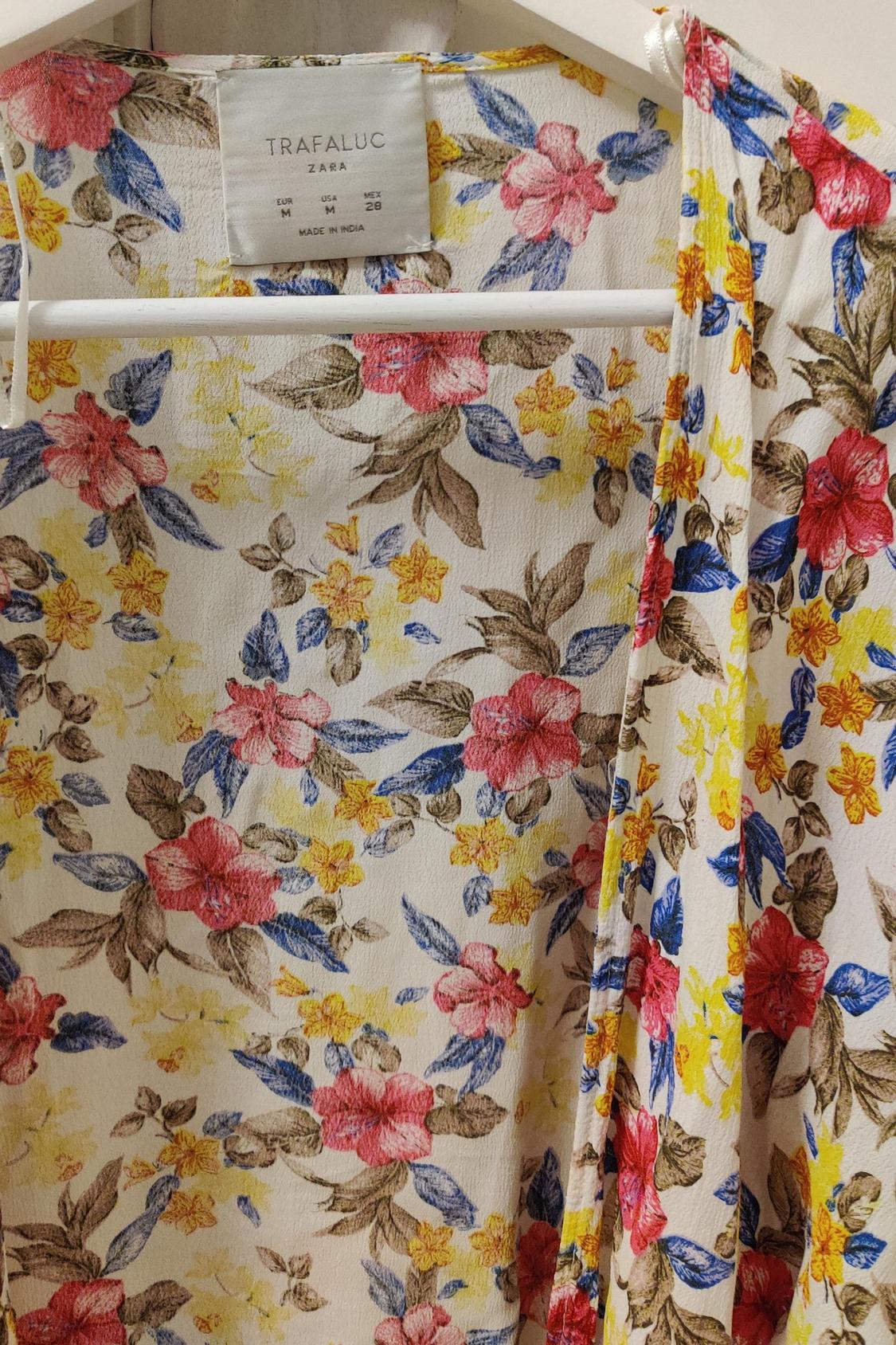 Floral fabric detail featuring a print of red and yellow flowers and blue leaves. Visible label with text 'TRAFALUC ZARA'.