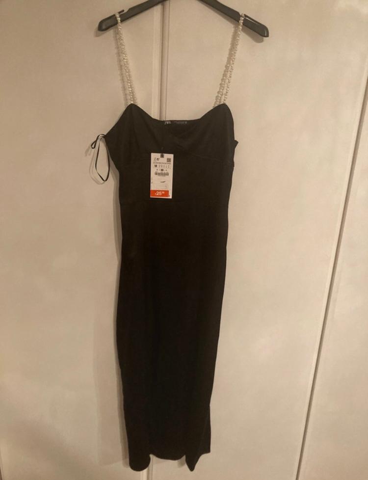 Black spaghetti strap dress hanging on a hanger, with a 25% discount tag visible in the centre.