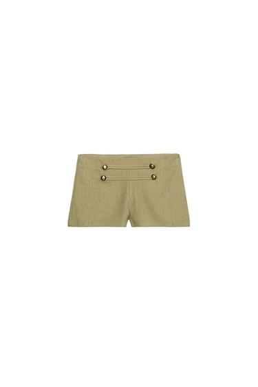 Front view of high-waisted khaki mini shorts. Featuring two horizontal tabs with four buttons on the front and vertical seams.